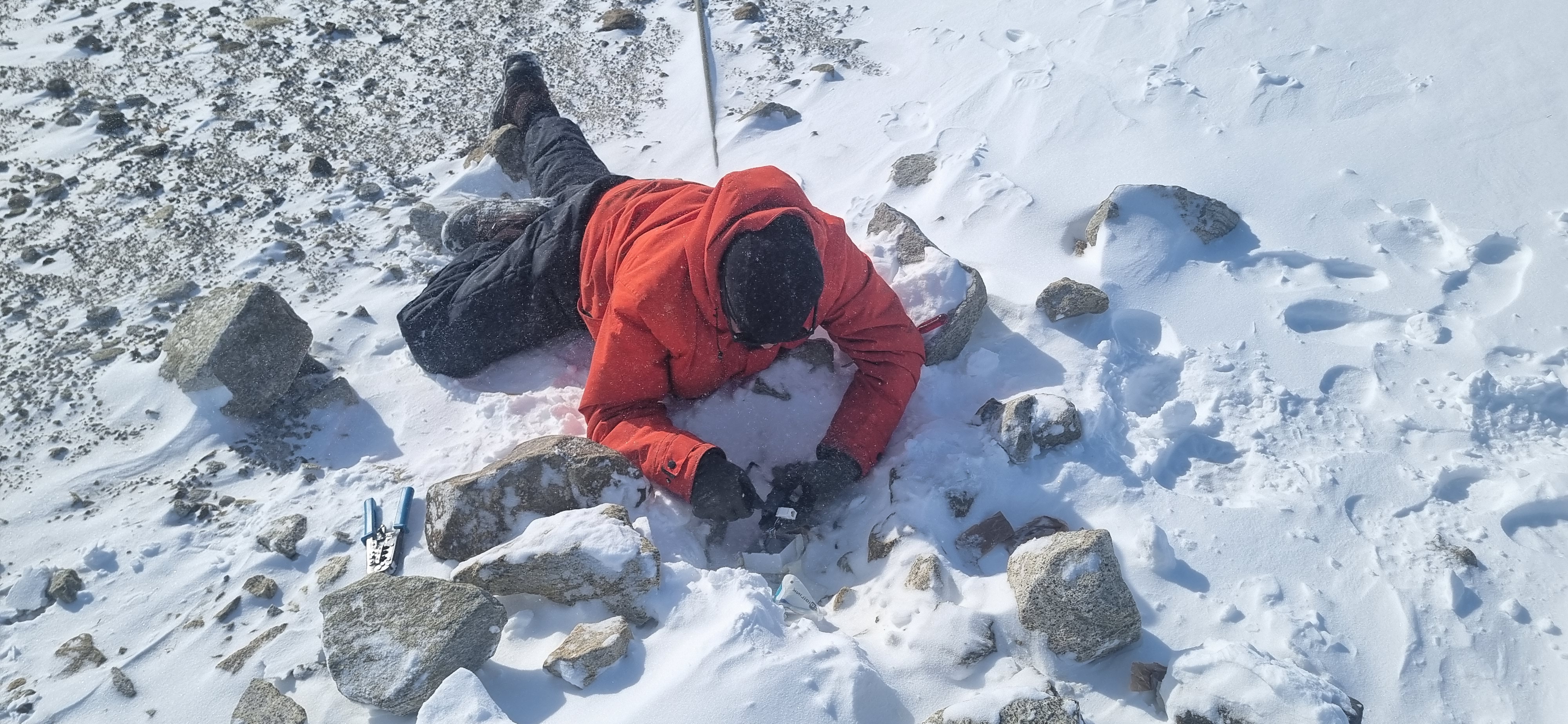 Repairing the ethernet line to restore WiFi at Maitri Summer Camp β prone on the Antarctic ice, tools in hand.